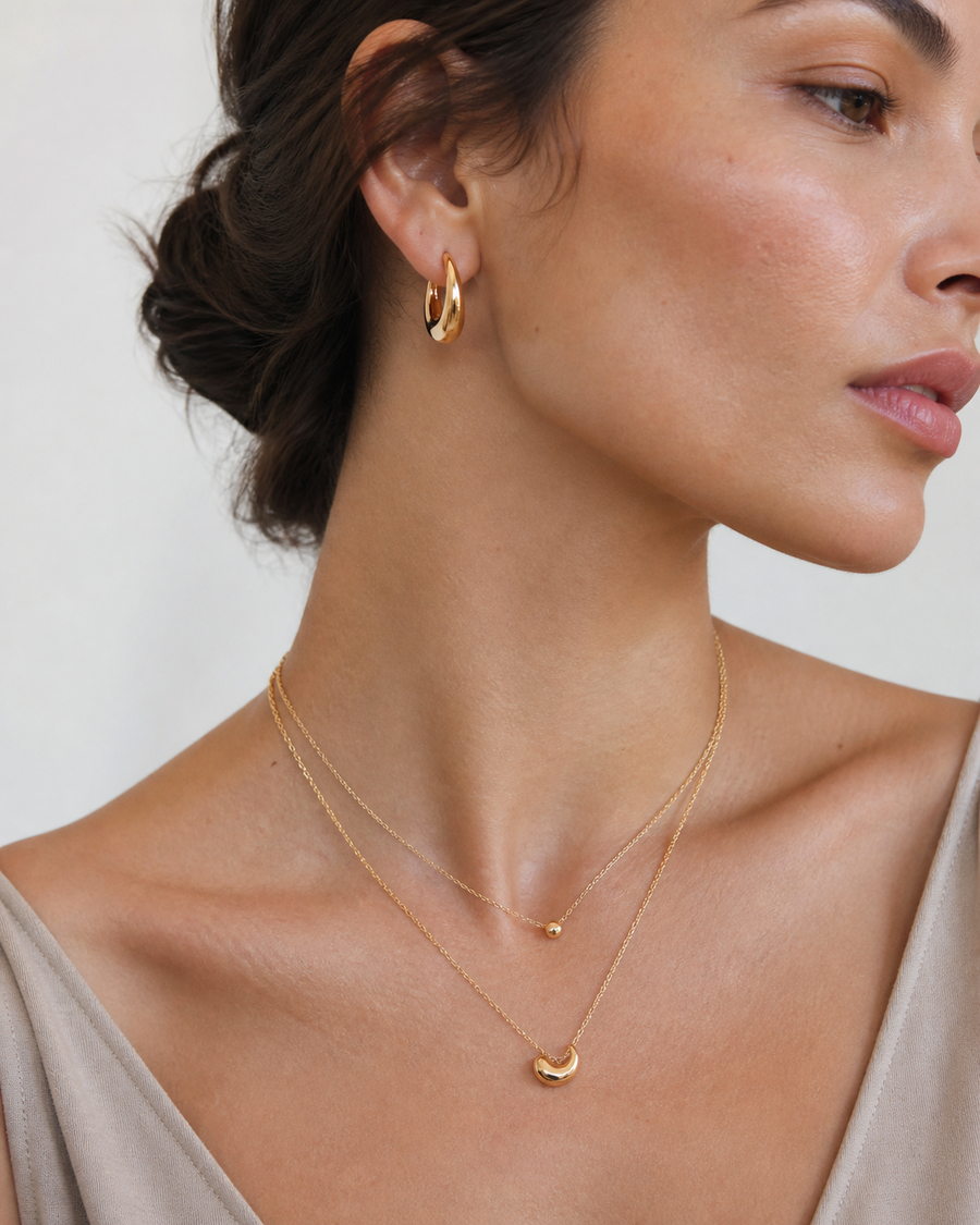 Model wearing Rare Matters sculptural earrings and layered necklaces