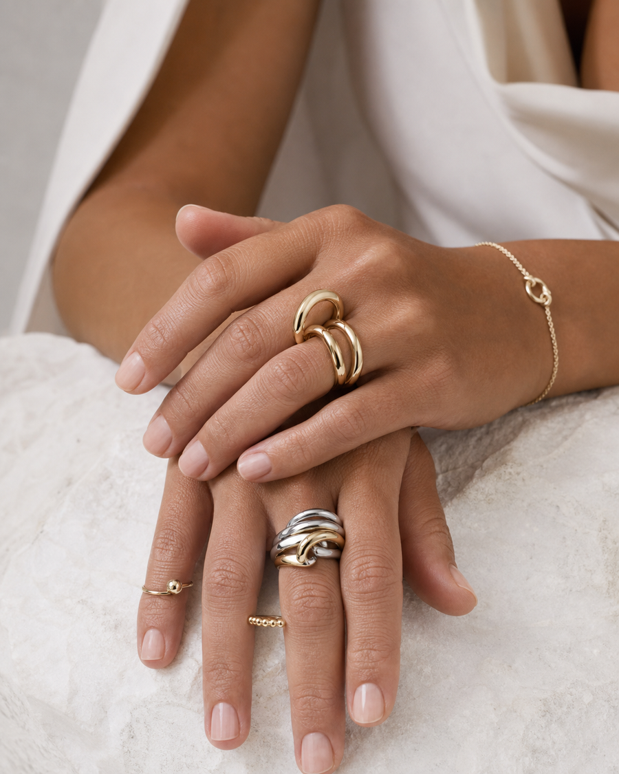 Hands wearing layered Rare Matters sculptural rings and bracelet